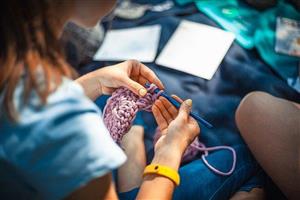 Young person crocheting with purple yarn.